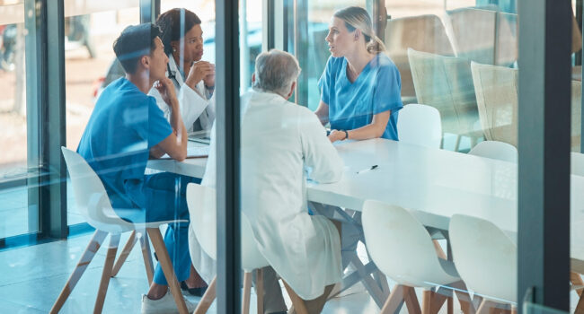 Doctors, healthcare team and meeting for a discussion, planning or training at table. Diversity men and women medical group talking about communication strategy, virus or surgery in a hospital education and training for DME organizations, sleep physicians, sleep related DME organizations, sleep laboratories